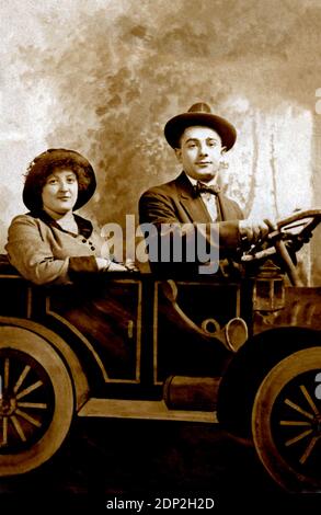 Antique photograph of a couple circa 1920 sitting in a photo studio by a paper automobile. Stock Photo