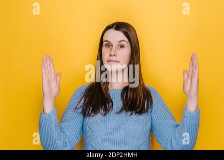 Surprise jeune femme isolée sur fond de studio jaune montrant grand geste avec les mains, belle femme émervetée, impressionné brunette fille démo Banque D'Images
