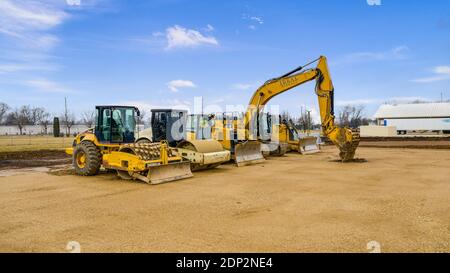 Équipement Caterpillar jaune installé sur un chantier. Cela comprend une chargeuse-pelleteuse, un compacteur, une pelle hydraulique et un bouteur. Banque D'Images