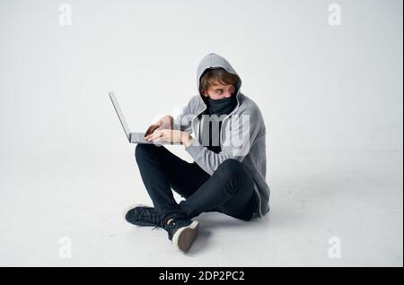 homme dans le noir gris avec ordinateur portable masque caché piratage ordinateur Banque D'Images