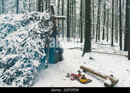Pique-nique d'hiver en forêt avec bougies de Noël et fruits planches en bois près d'un abri de survie de brousse Banque D'Images