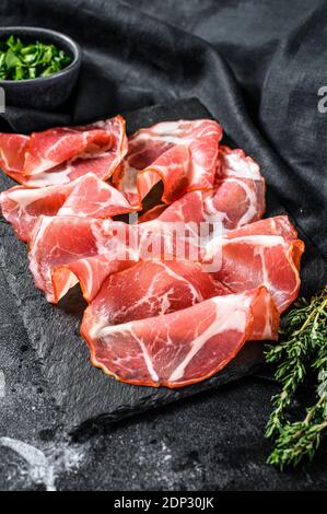 Bacon roulé italien Pancetta Piacentina. Viande de porc. Arrière-plan noir. Vue de dessus. Banque D'Images