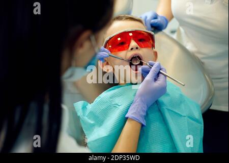 Dentiste examinant les dents du petit garçon en clinique dentaire Banque D'Images