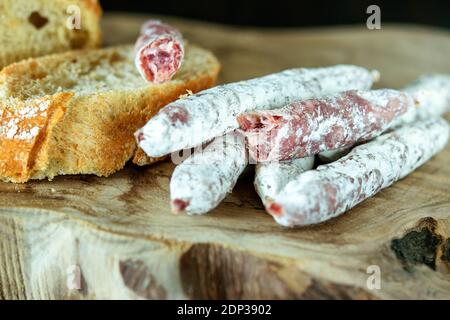 Des doigts délicieux de fuet de saucisse espagnole et quelques tranches de pain blanc sur le bois naturel de la cuisine planche. Banque D'Images