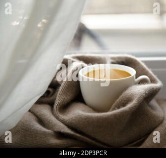 tasse de café aromatique et écharpe en cachemire sur le rebord de la fenêtre le matin d'hiver Banque D'Images