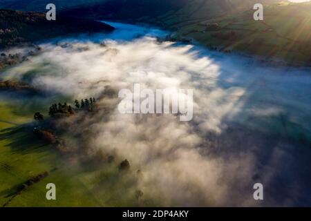 Vue aérienne d'une belle vallée et d'une zone rurale vallonnée remplie de brouillard en fin d'après-midi de soleil. Banque D'Images