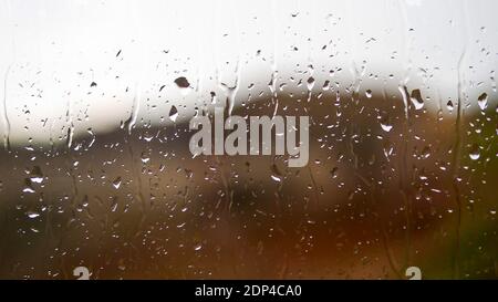 Gouttes de pluie sur la fenêtre, belles gouttes coulant le long du verre, gros plan. Banque D'Images