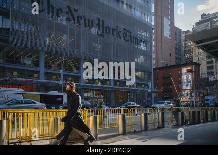 Manhattan, New York. 15 décembre 2020. Un homme portant un masque marche devant le bâtiment du New York Times sur la 8e avenue de Midtown. Banque D'Images