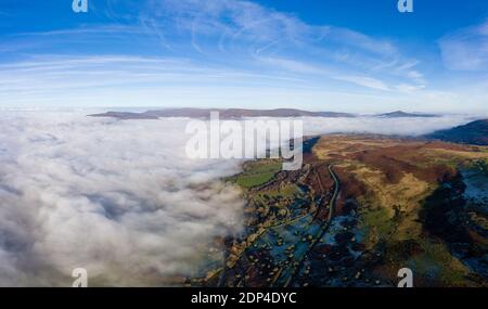 Panorama aérien d'une route de montagne étroite et sinueuse émergeant au-dessus d'une rive de brouillard dans une vallée rurale (pays de Galles) Banque D'Images