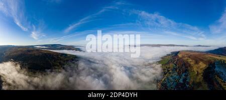 Panorama aérien d'une route de montagne étroite et sinueuse émergeant au-dessus d'une rive de brouillard dans une vallée rurale (pays de Galles) Banque D'Images