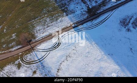 Photo de drone d'une voiture blanche qui passe de la lumière à l'ombre sur route en hiver Banque D'Images