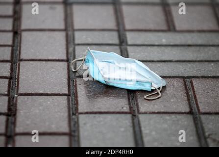 A discarded face mask lies on the street during the coronavirus pandemic. Stock Photo