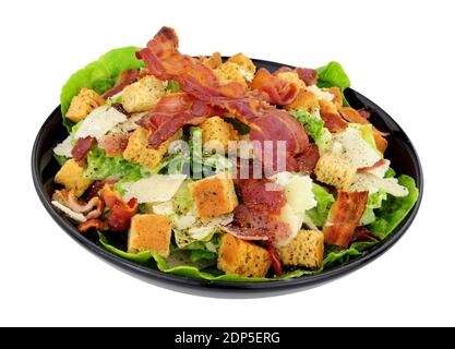 Salade César au bacon avec laitue romaine et copeaux de fromage parmesen servi dans un plat noir isolé sur fond blanc Banque D'Images