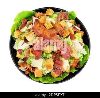 Salade César au bacon avec laitue romaine et copeaux de fromage parmesen servi dans un plat noir isolé sur fond blanc Banque D'Images