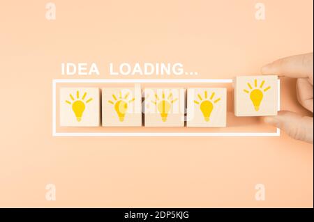concept de chargement d'idée. Main de mise en forme de bloc cube en bois avec ampoule. Prenez à la main un bloc de cube en bois avec de la lumière. Barre de chargement presque complète avec Banque D'Images