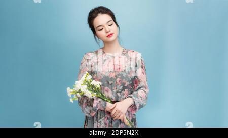 Portrait de la femme à l'aspect agréable a un maquillage minimal, large sourire, reçoit des fleurs en occasion spéciale, isolé sur fond bleu clair Banque D'Images