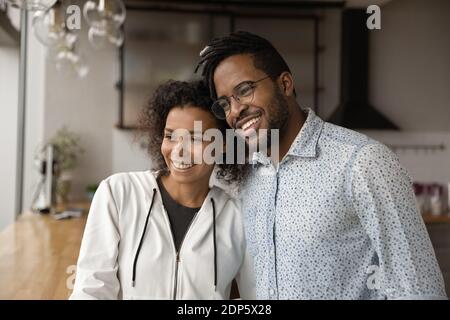 Un couple biracial souriant regarde en rêve à distance Banque D'Images