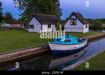 Bateaux sur la rivière Bure et huttes de chaume près de Coltimath au crépuscule, Norfolk Broads, Norfolk, Angleterre, Royaume-Uni, Europe Banque D'Images