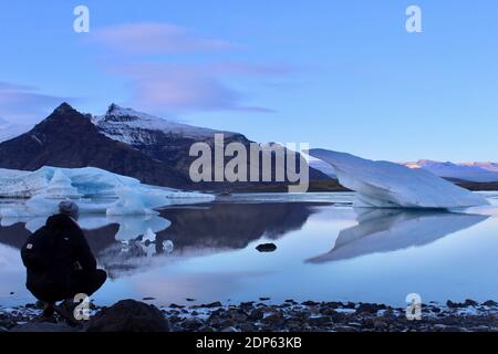 Homme prenant une photo du lac Jokulsarlon en Islande Banque D'Images