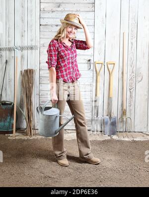 femme dans jardin potager avec arrosoir sur bois blanc jeter l'arrière-plan avec les outils de jardinage Banque D'Images