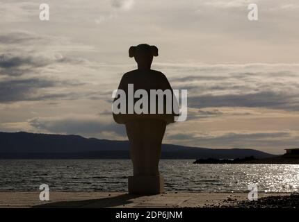 Silhouette de non nageur portant une sculpture de ceinture de sauvetage à bol, île de Brac, Dalmatie, Croatie. Banque D'Images