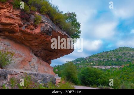 Une formation de roche rouge avec des arbustes sur le sommet, une colline pittoresque en arrière-plan Banque D'Images