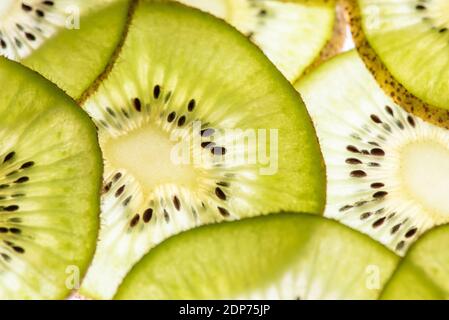 Photo macro d'un délicieux kiwi mûr coupé en cercles avec rétro-éclairage sur la lumière. Vue de dessus Banque D'Images