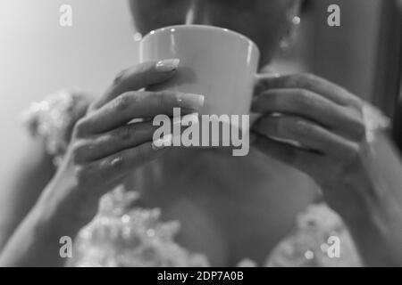 Une photo en gros plan en niveaux de gris d'une mariée buvant un café Banque D'Images