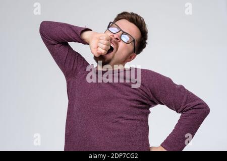 Homme mature et fatigué en lunettes bâillant et étirant. Prise de vue en studio Banque D'Images