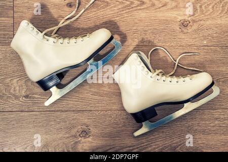 patineuses blanches sur fond de bois. photo teintée Banque D'Images