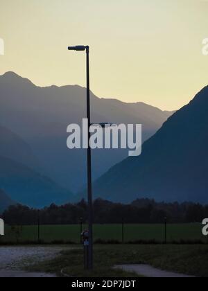 Un cliché vertical d'une lampe de rue sur un champ avec silhouettes de montagne en soirée sur le fond Banque D'Images