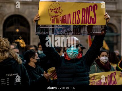 Barcelone, Espagne. 19 décembre 2020. Un activiste catalan de gauche détient un écriteau « payé par les riches » alors qu'il proteste contre les mesures anti-covid19, les fermetures et les limitations des contacts sociaux imposées par le gouvernement catalan en raison de la propagation accélérée du coronavirus et de la demande de règlement de la crise économique qui en résulte « les riches ». Credit: Matthias Oesterle/Alamy Live News Banque D'Images