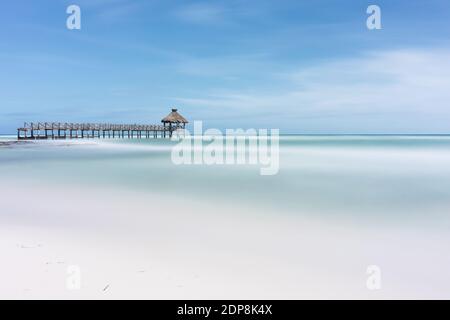 Une belle photo d'un océan calme ou d'une mer côte avec un petit pont en bois sous le ciel bleu Banque D'Images