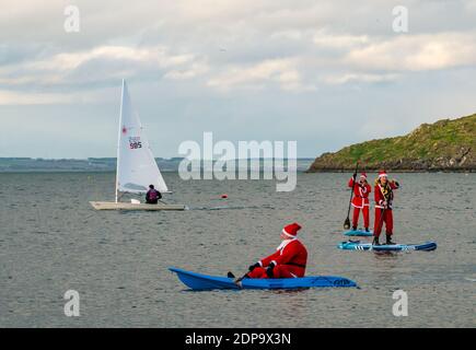 North Berwick, East Lothian, Écosse, Royaume-Uni, 19 décembre 2020. Paddle Boarding Santas pour la charité: Une initiative de la communauté locale par North Berwick News and Views appelée « Christmas Cheer » recueille plus de 5,000 £ de fonds pour les familles dans le besoin. Les paddle boarders sont habillés en costumes de Santa avec un bateau à voile passant par Banque D'Images