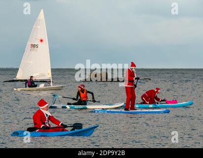 North Berwick, East Lothian, Écosse, Royaume-Uni, 19 décembre 2020. Paddle Boarding Santas pour la charité: Une initiative de la communauté locale par North Berwick News and Views appelée « Christmas Cheer » recueille plus de 5,000 £ de fonds pour les familles dans le besoin. Les paddle boarders sont habillés en costumes de Santa avec un bateau à voile passant par Banque D'Images