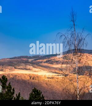 Le coucher du soleil de printemps illumine le côté de la montagne au loin. Banque D'Images