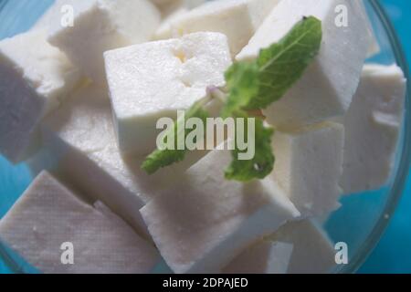 Paneer indien fait maison à base de lait frais et de jus de citron, coupé en dés dans un bol en bois sur fond de pierre grise. Orientation horizontale. Banque D'Images