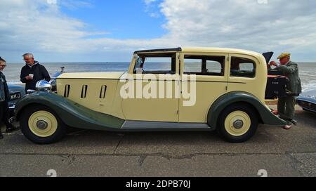 Belle voiture de voiture de couleur crème Classic Rolls Royce garée sur la promenade du front de mer avec la plage et la mer en arrière-plan. Banque D'Images