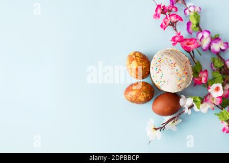 œufs peints et gâteau de pâques sur fond bleu avec fleurs printanières avec un espace de copie Banque D'Images