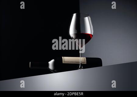 Verre et bouteille de vin rouge sur fond sombre. Copier l'espace. Banque D'Images