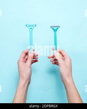 Les mains des femmes tiennent deux rasoirs pour une épilation sur fond bleu. Vue de dessus, minimalisme, style de pose plate Banque D'Images