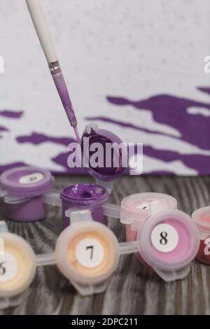 Brosses et peintures pour la peinture. À proximité se trouve un fragment d'une image peinte. Sur les planches de pin noir. Peinture par numéros. Banque D'Images