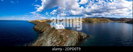 Grèce, île de Kea Tzia. Drone, vue panoramique aérienne du phare et de l'église d'Agios Nikolaos sur un cap rocheux, ciel bleu nuageux et rippé Banque D'Images