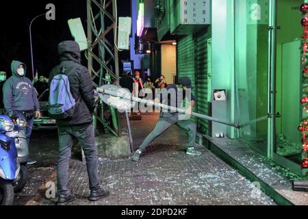 Beyrouth, Liban. 19 décembre 2020. Un militant anti-gouvernemental utilise un panneau de signalisation pour briser la fenêtre d'une banque locale lors d'une manifestation en raison de l'augmentation des frais de scolarité dans un contexte de crise économique aiguë et d'impasse politique qui engloutit le pays. Credit: Marwan Naamani/dpa/Alamy Live News Banque D'Images