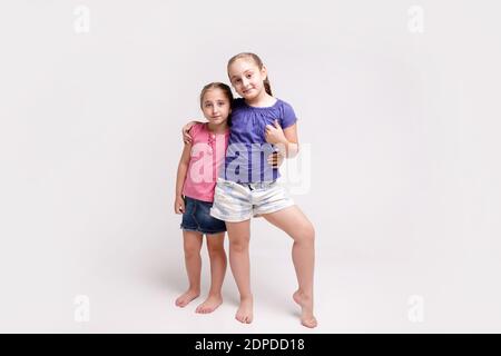 Deux petites sœurs mignonnes d'âges différents regardant l'appareil photo souriant montrant le pouce de geste de la main vers le haut. Portrait bébés heureux Banque D'Images