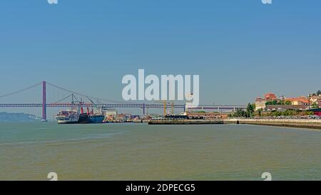 Cargo et pont du 25 avril sur le Tage dans le port de Lisbonne, Portugal Banque D'Images