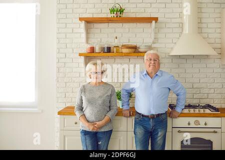 Heureux couple senior grands-parents debout et regardant la caméra ensemble dans la cuisine Banque D'Images