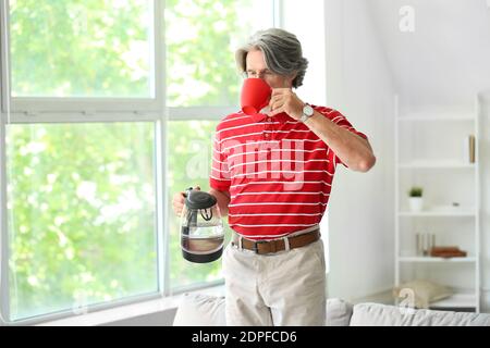 Homme mature avec bouilloire électrique pour boire du thé dans la cuisine Banque D'Images