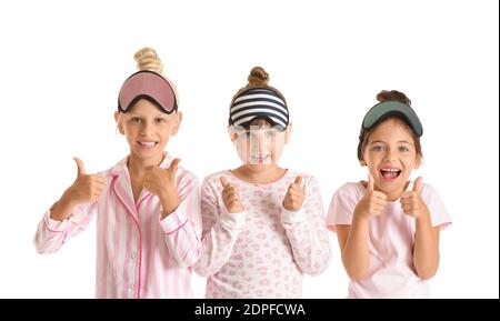 Jolies petites filles en pyjama et masques de sommeil sur blanc arrière-plan Banque D'Images