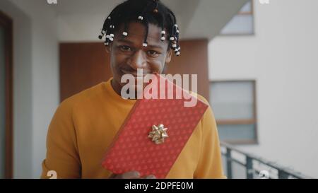 Portrait d'un homme noir afro-américain tenant une boîte cadeau. Achats de Noël en ligne . Photo de haute qualité Banque D'Images